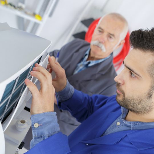 male technician is repairing a printer assited by senior